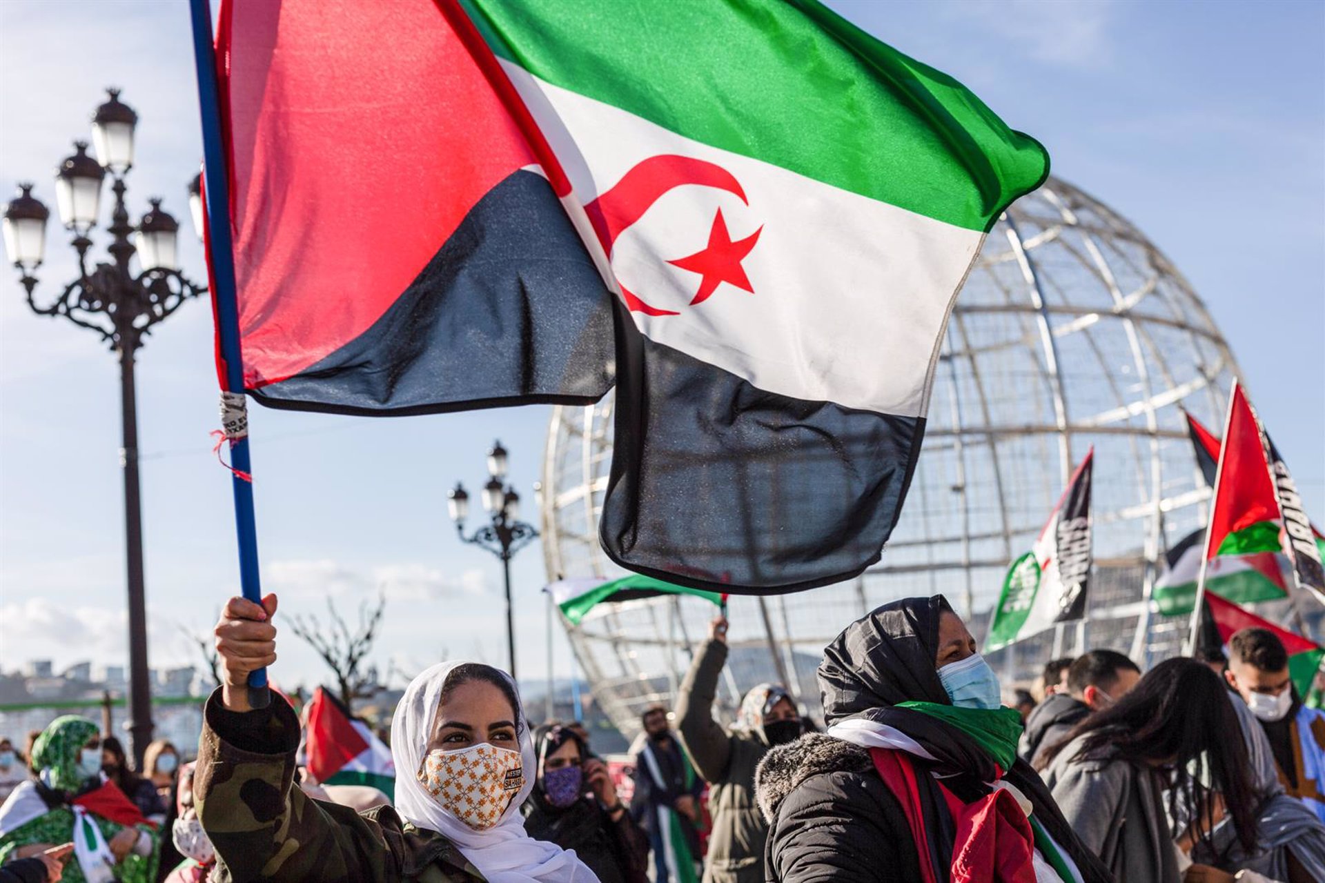Personas ondeando la bandera del Sáhara Occidental frente polisario