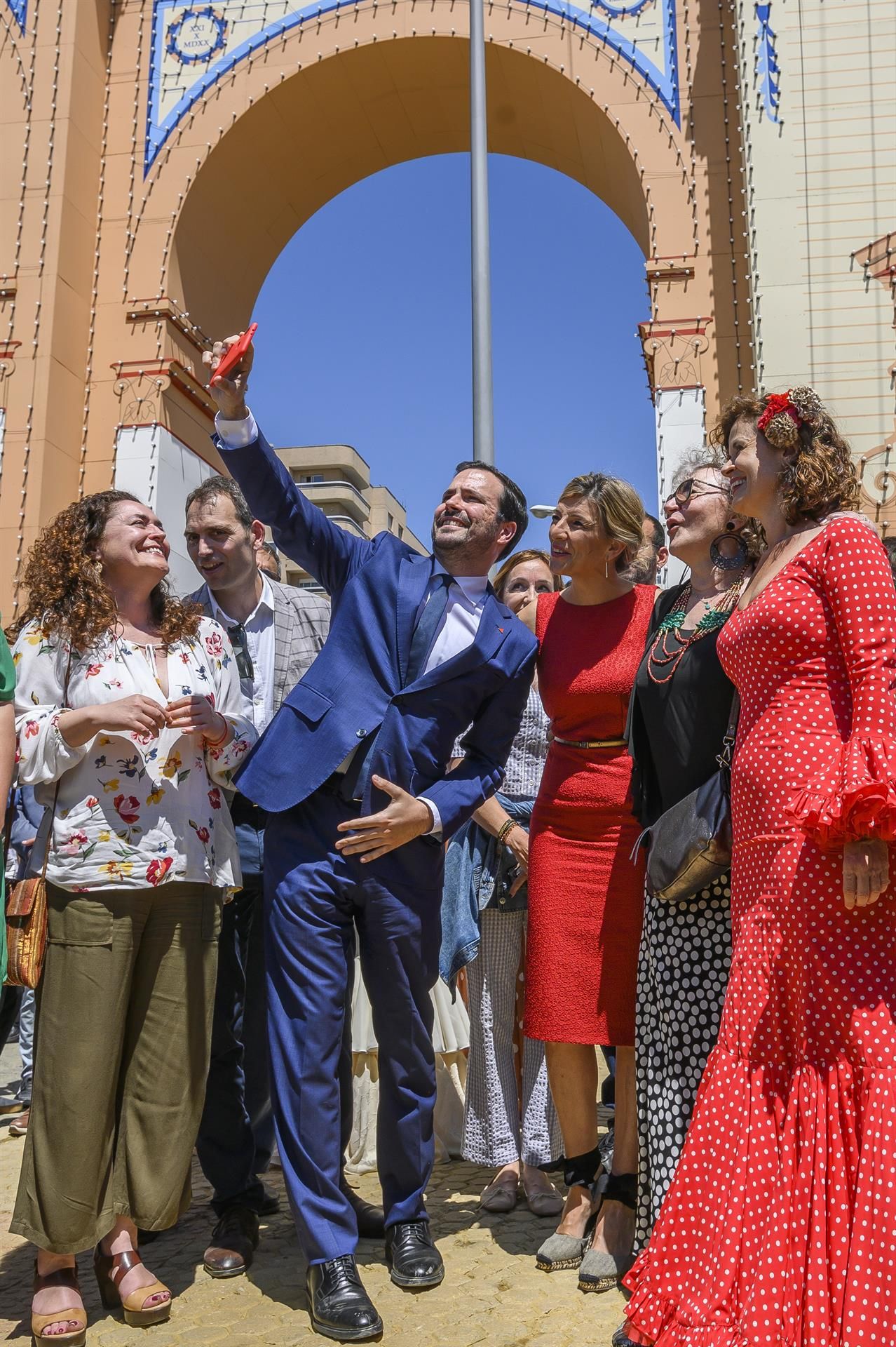 La vicepresidenta segunda del Gobierno y ministra de Trabajo, Yolanda Díaz, y el ministro de Consumo y líder de IU, Alberto Garzón, se hacen una fotografía con varias personas junto a la portada de la Feria de Abril de Sevilla