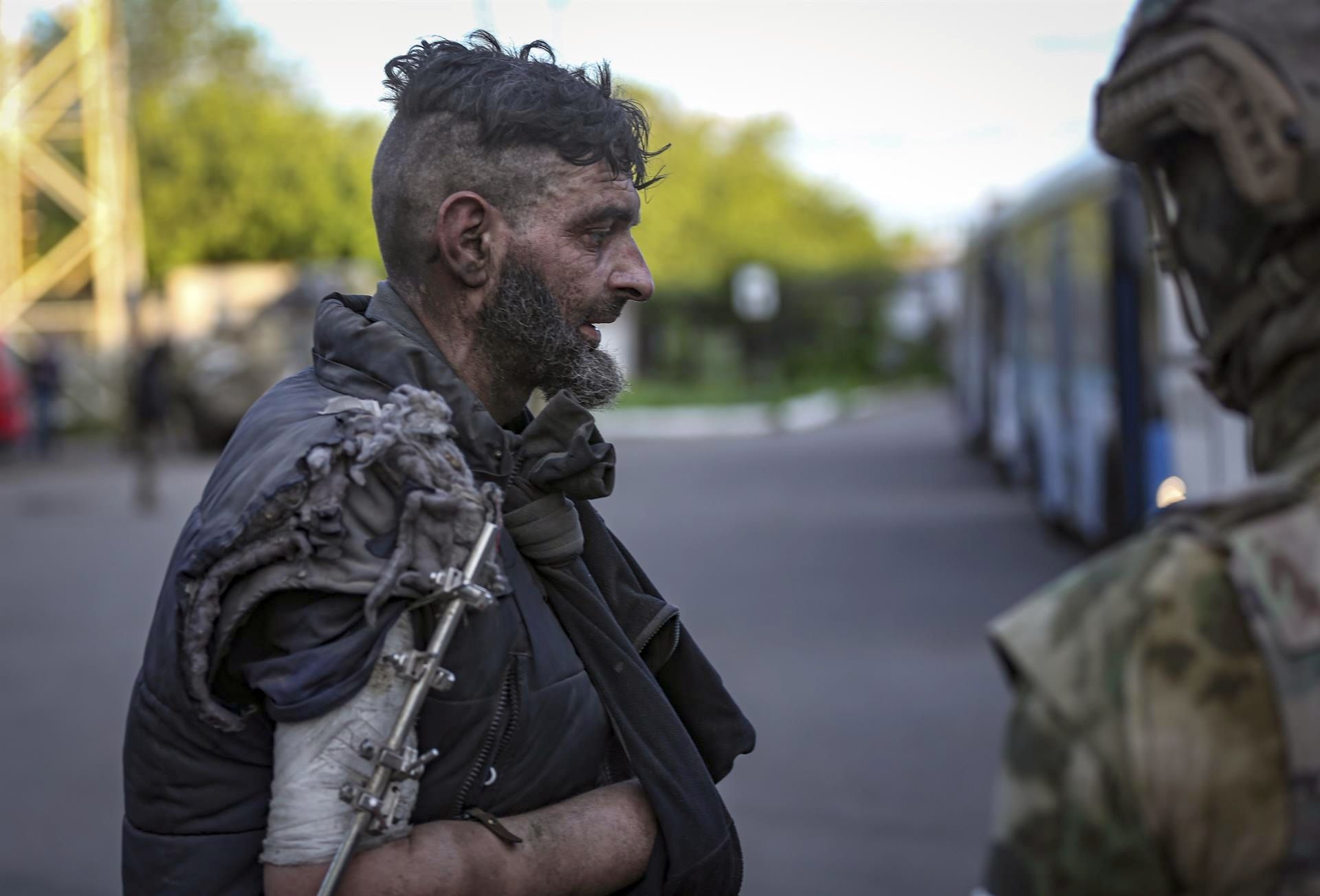 La autoproclamada milicia RPD (R) observa a un militar ucraniano subir a un autobús mientras es evacuado de la planta siderúrgica sitiada de Azovstal
