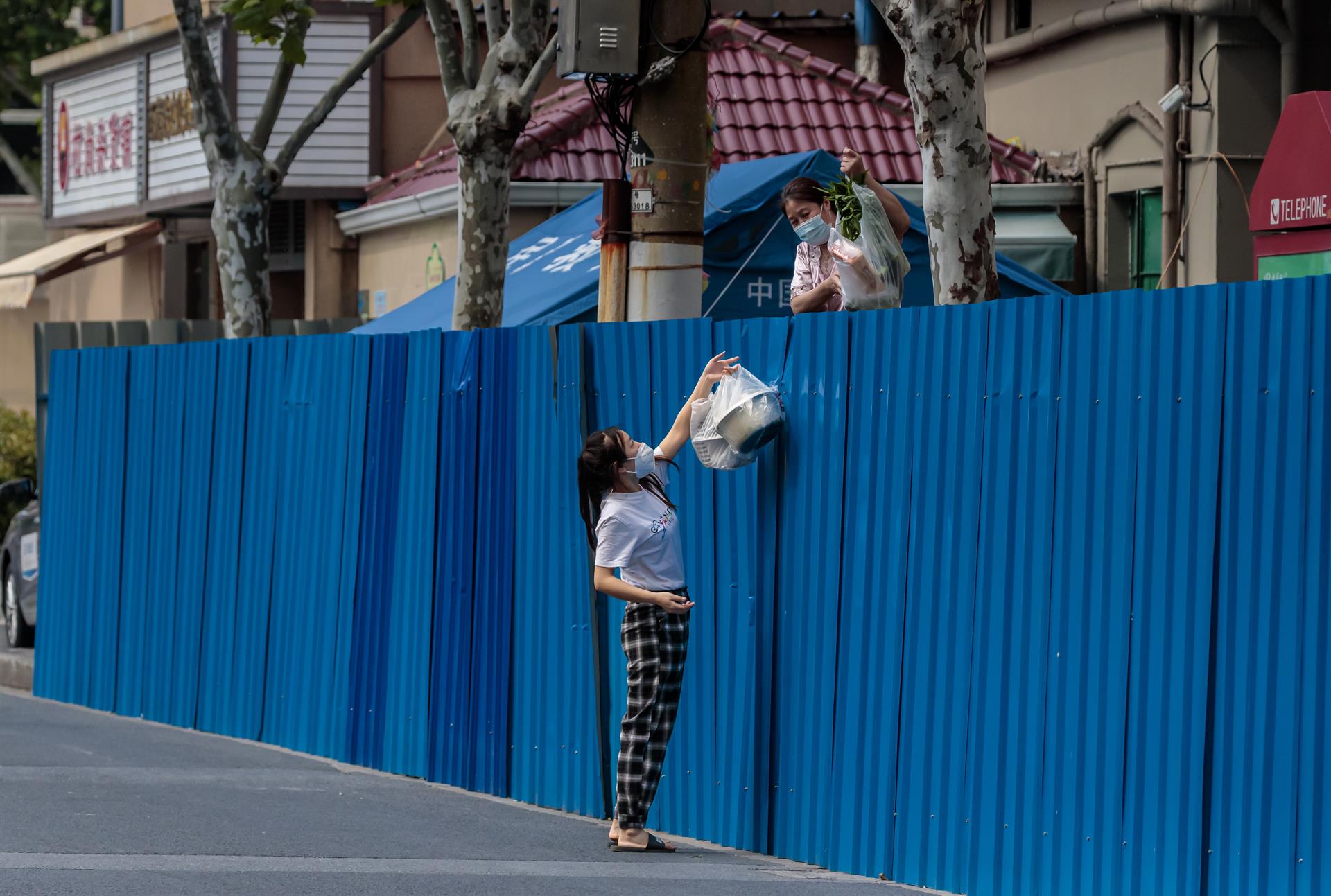 Mujeres confinadas se pasan suministros a través de la valla (Shanghái)
