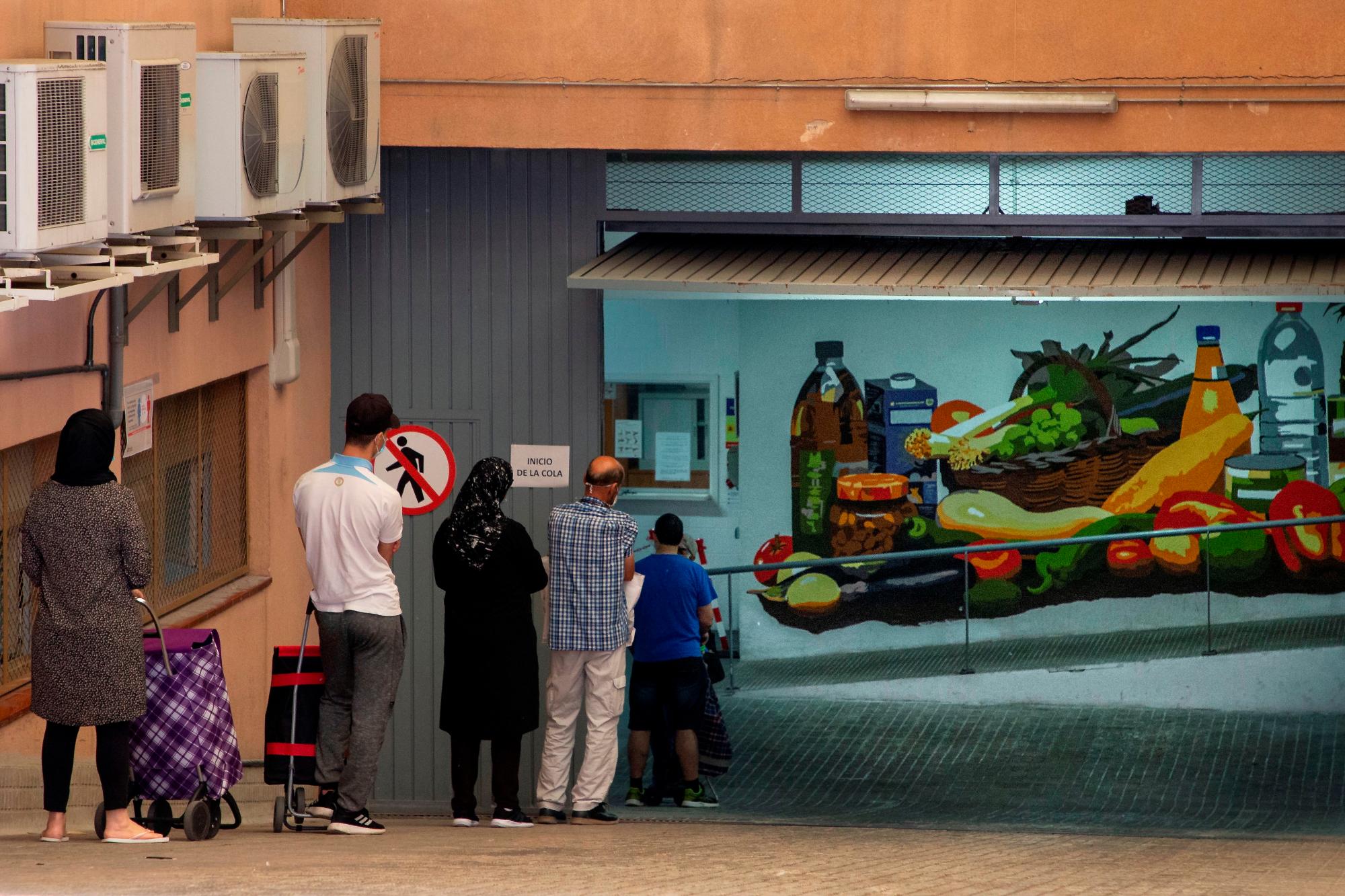 Varias personas, a la espera de recoger alimentos en el almacen de la Cruz Roja en Mataró (Barcelona)