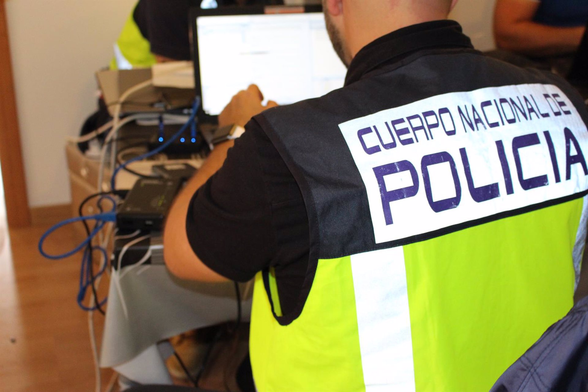 Agentes de la Policía Nacional revisan un ordenador en la detención de un hombre por estafa.