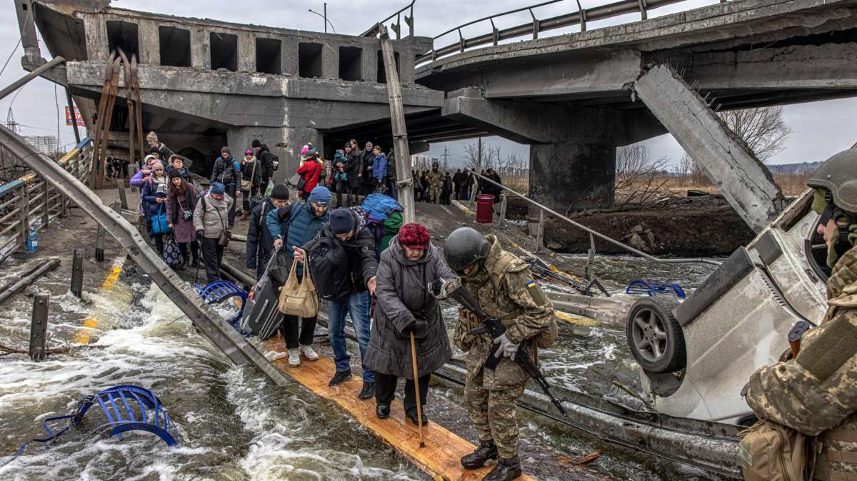 Primer aniversario de la guerra en Ucrania. En la imagen, varias personas cruzan un puente destruido por los bombardeos rusos en Irpin en los primeros días de la invasión rusa.