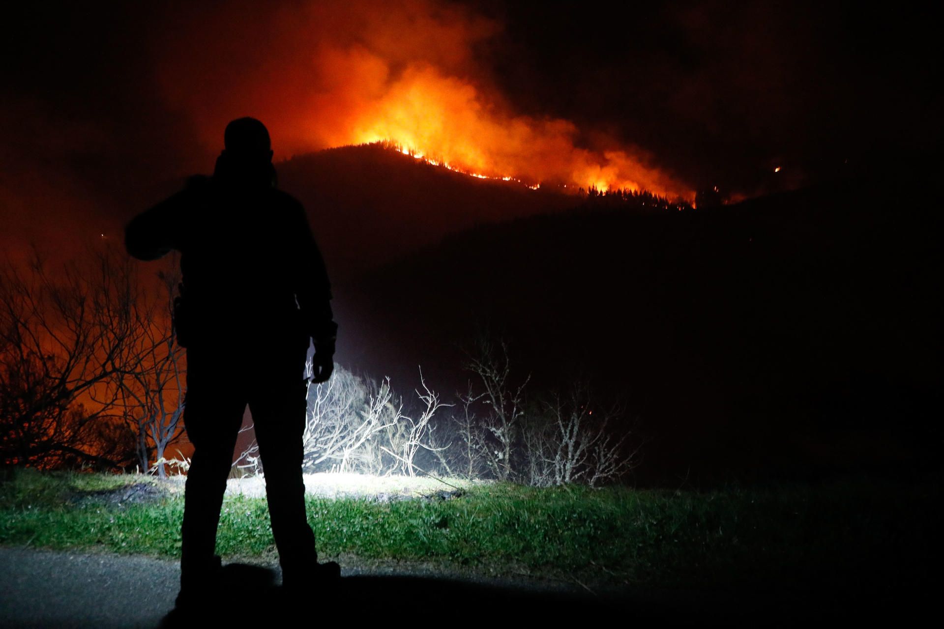 Un Guardia Civil observa las llamas en el monte en Cortevella, Lugo, este jueves 30 de marzo.