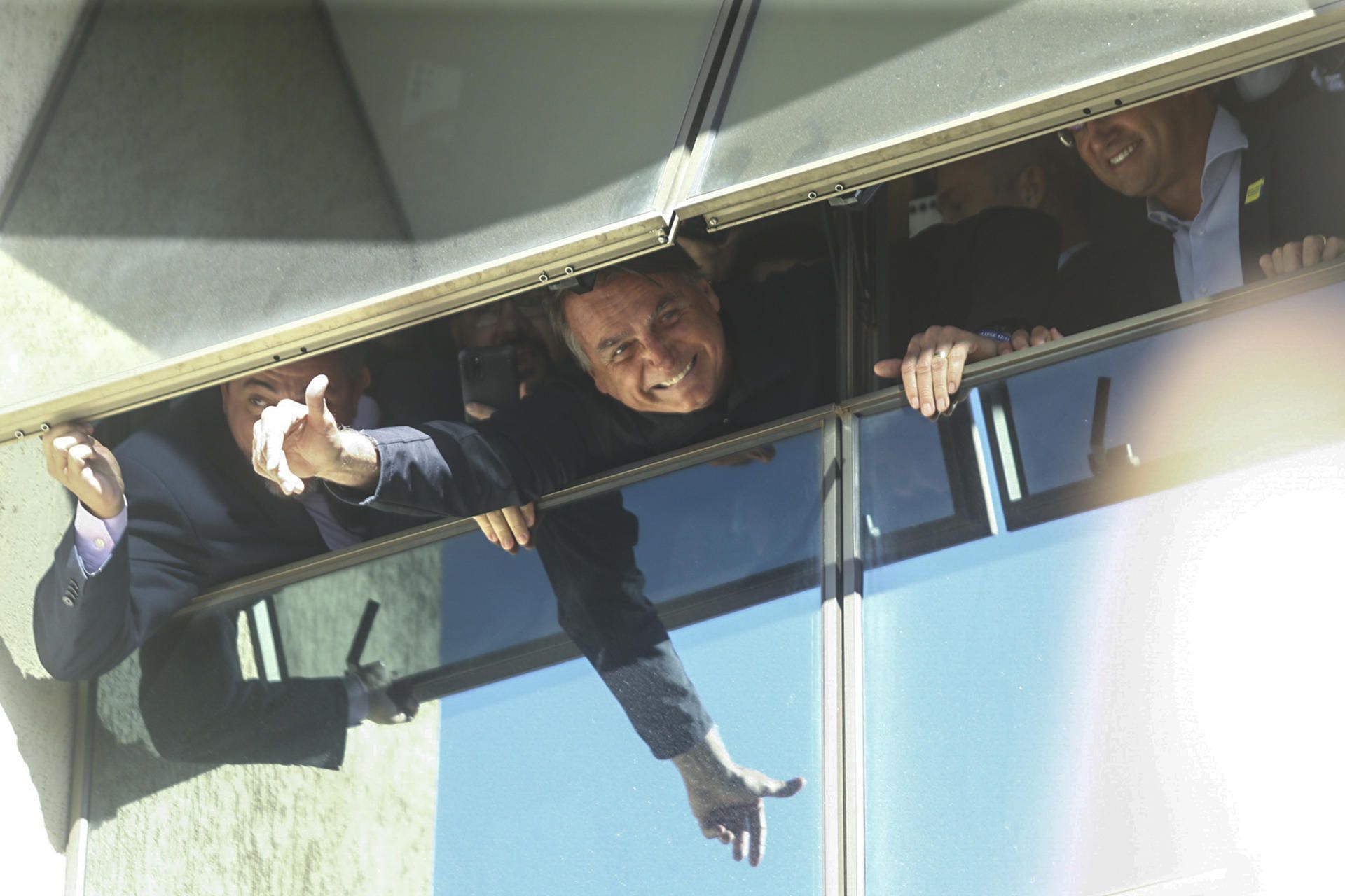 El expresidente brasileño Jair Bolsonaro saluda desde una ventana en la sede de su partido este jueves, en Brasilia.