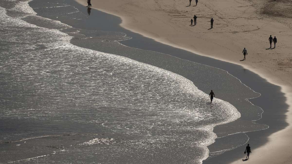 Tiempo Varias personas pasean por la playa de La Concha en Suances este viernes.