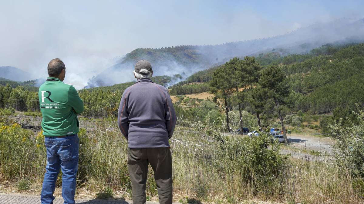 Dos personas observan las llamas del fuego que afecta a la población de Pinofranqueado, en las Hurdes.