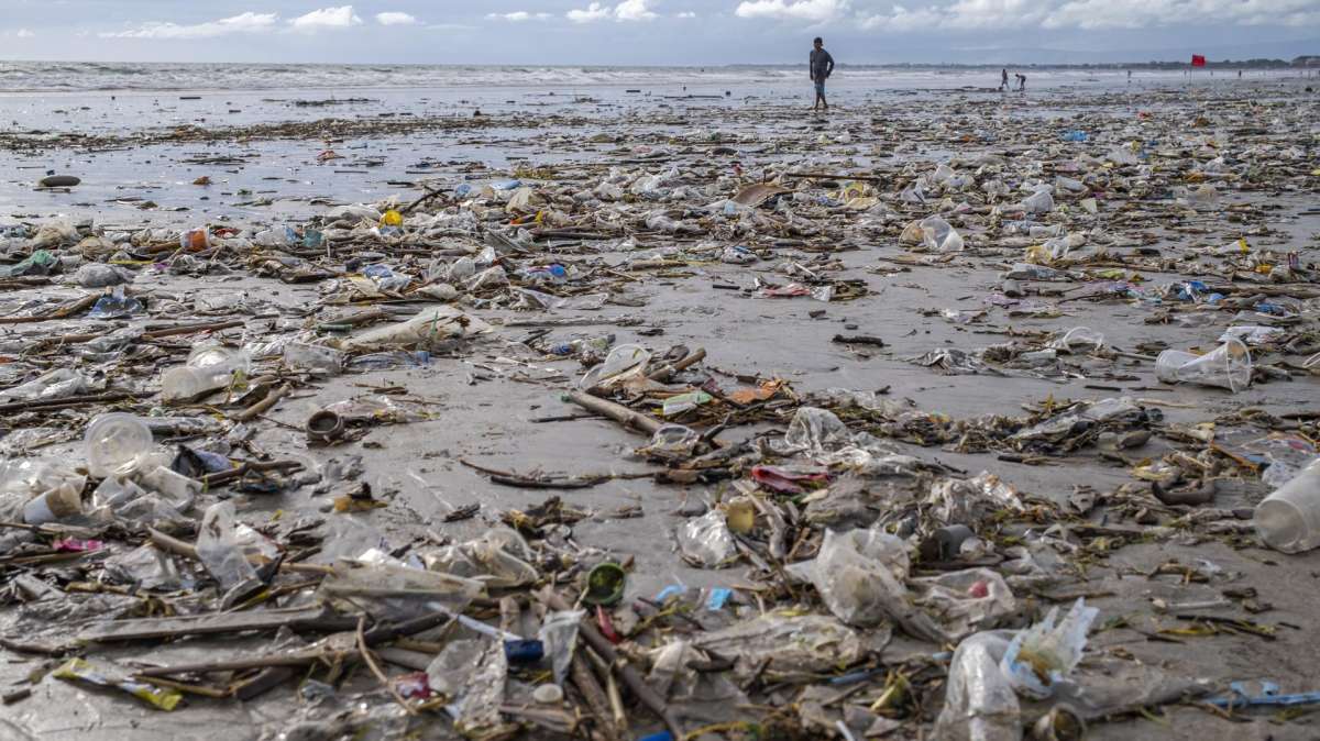 ONU Un hombre camina entre plásticos por Kuta Beach en Bali, Indonesia.