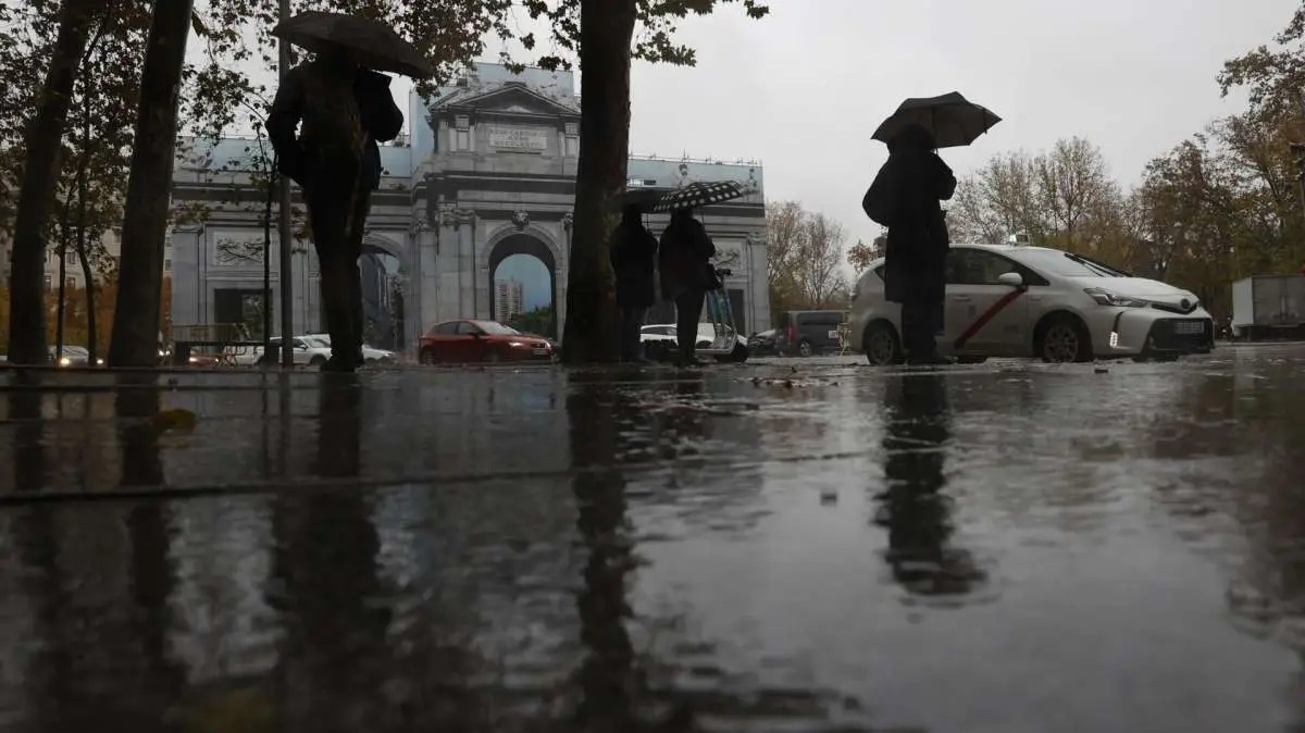 Varias personas se protegen con el paraguas de la lluvia en Madrid.