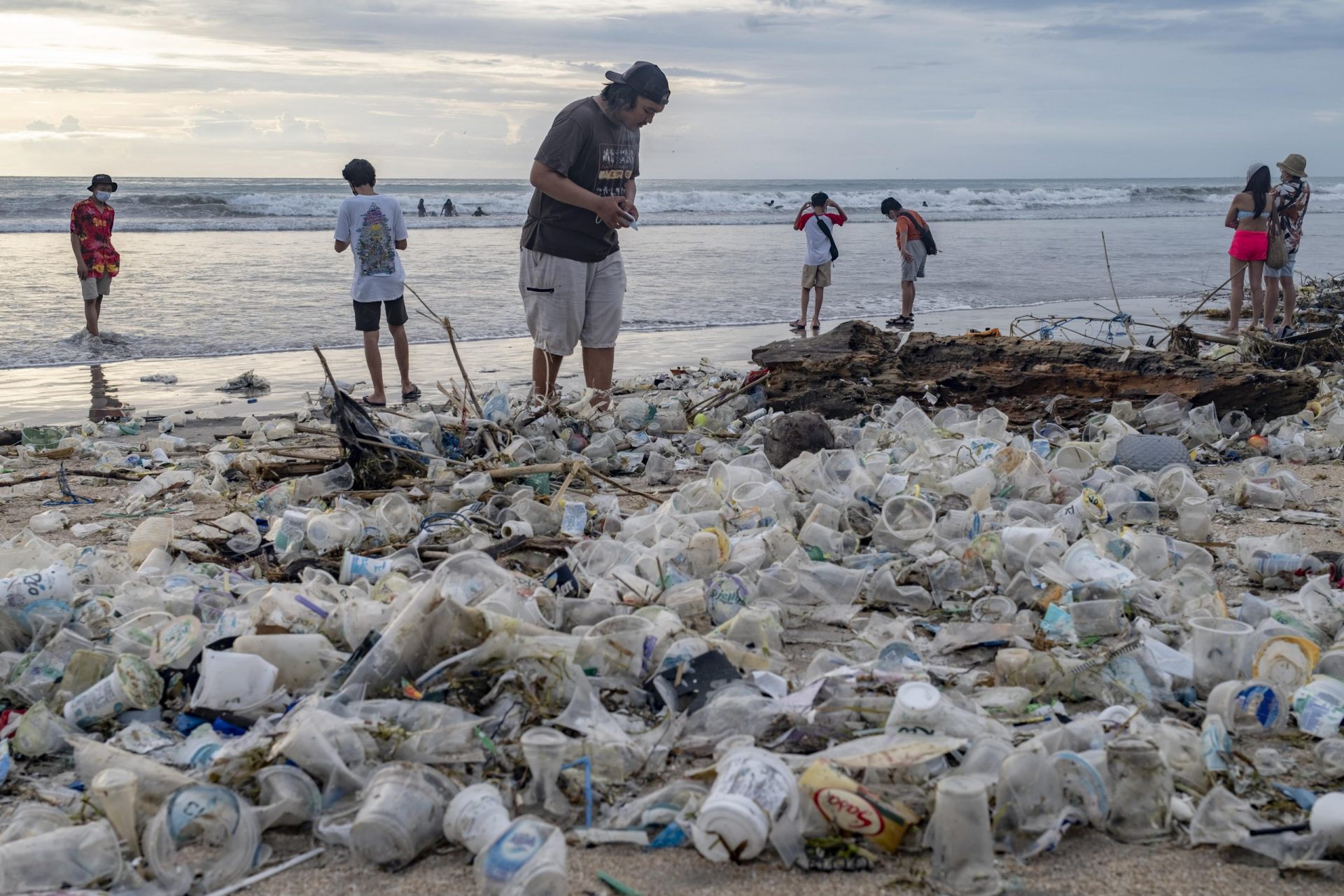 Varias personas caminan por una playa cubierta de plásticos en Bali, Indonesia.