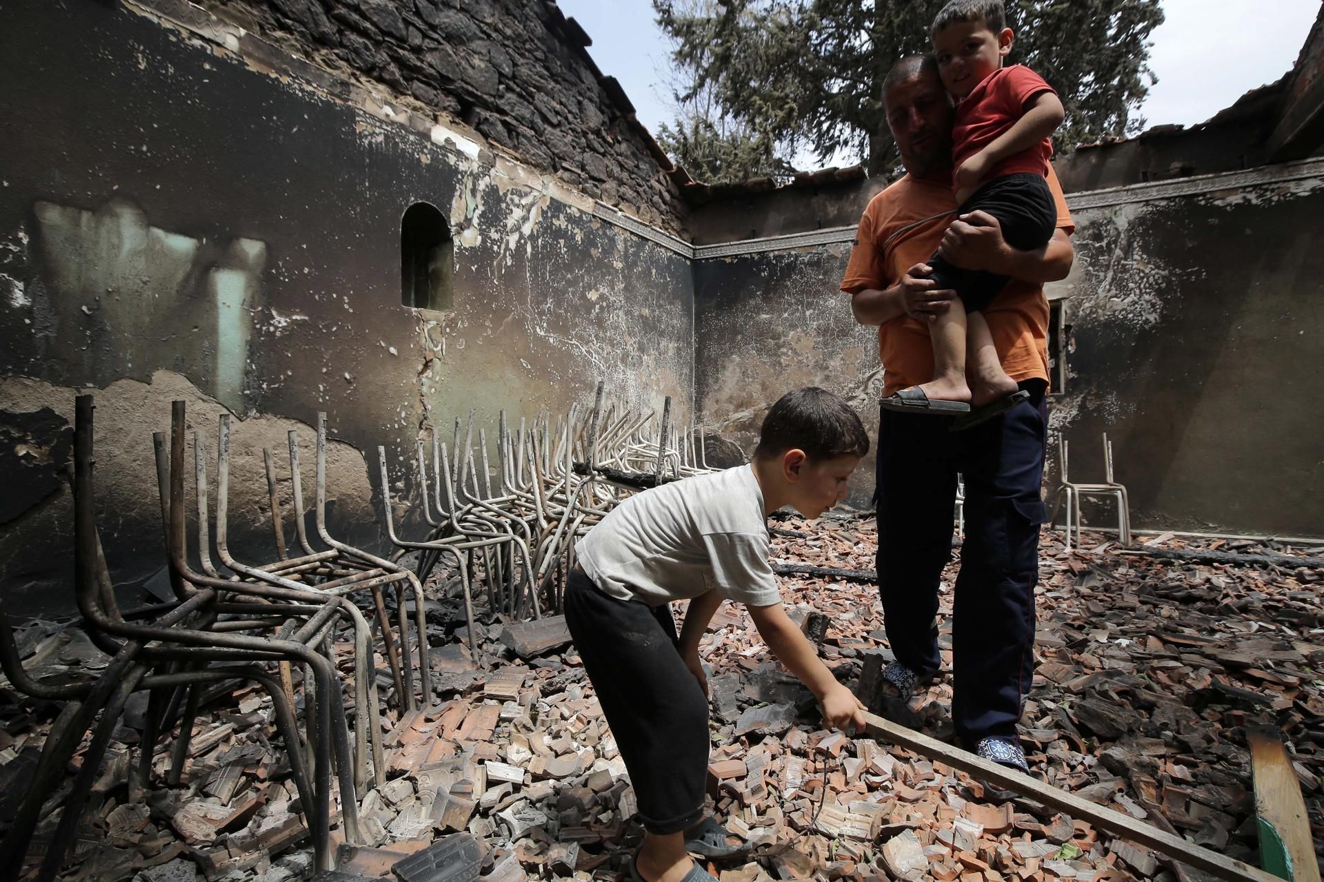 Un argelino con sus hijos inspecciona su casa quemada en el pueblo de Oeud Das, al este de Argel.