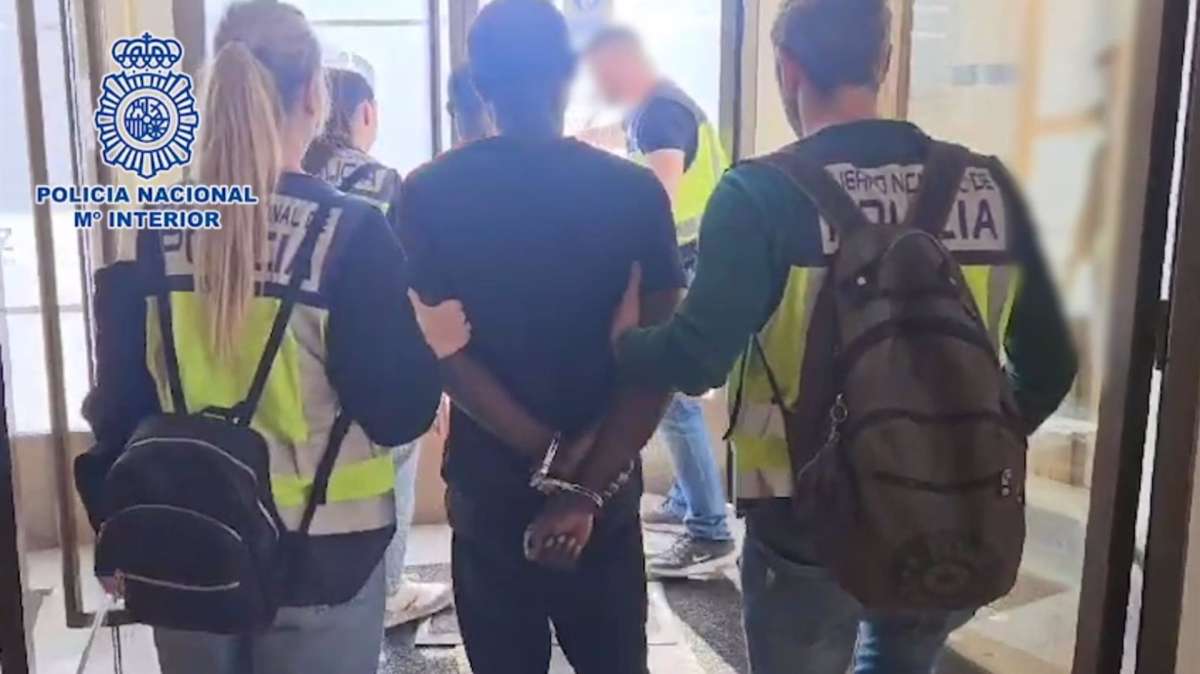 Agentes de la Policía Nacional custodian a uno de los detenidos.