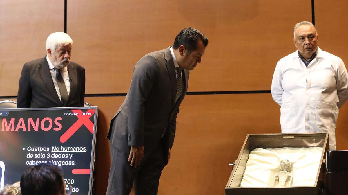 El diputado mexicano Sergio Carlos Gutiérrez (c) examina el supuesto cuerpo de uno de los dos supuestos extraterrestres exhibidos en el Congreso.