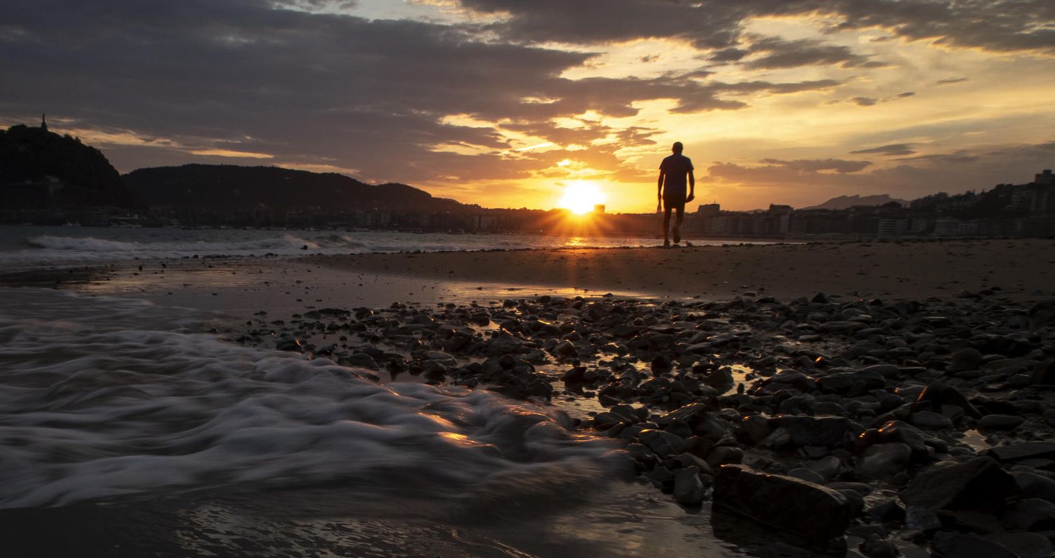Un hombre pasea al amanecer por la playa de Ondarreta, en San Sebastián.