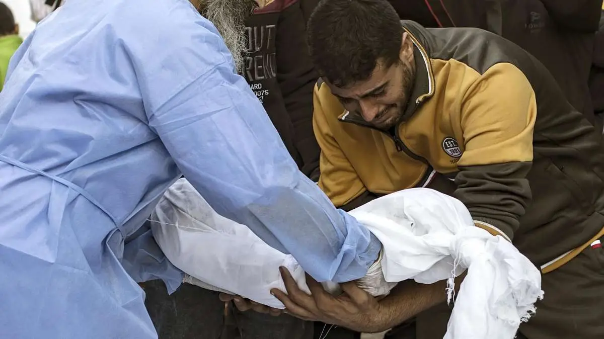 Un sanitario entrega el cuerpo sin vida de un niño a su padre en Gaza.