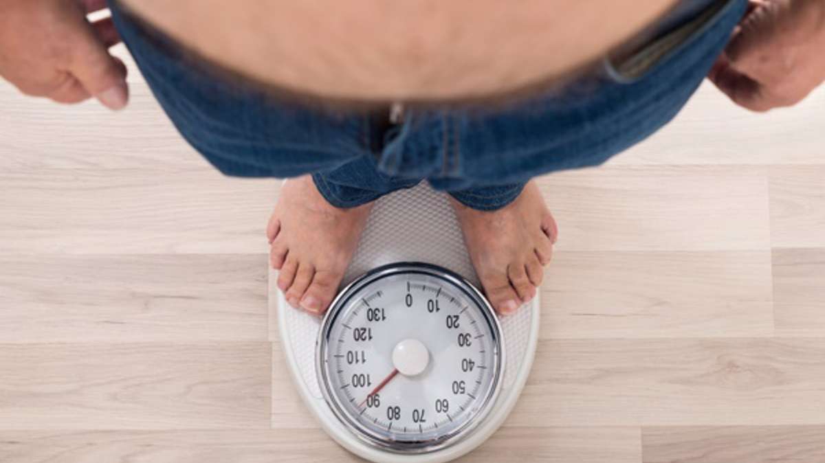 obesidad Un hombre mide su peso en una báscula.
